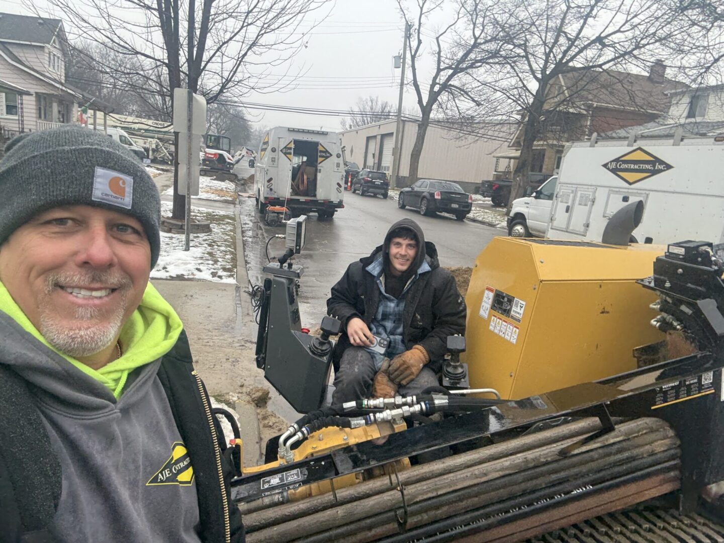 Two men working outdoors with metal pipes and machinery.