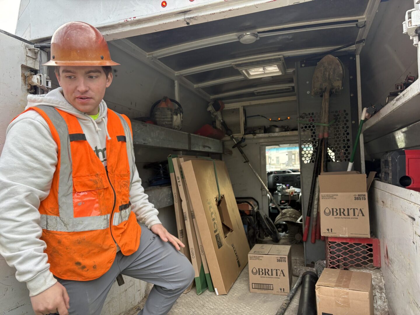 Construction worker in safety gear inside a cluttered storage area.