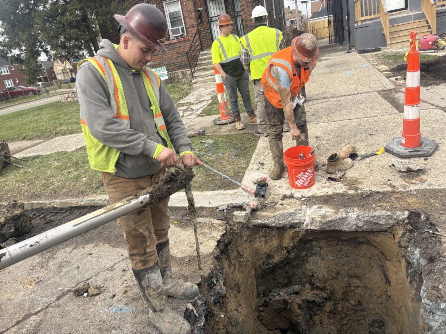 Construction workers repairing a street with safety gear and tools.