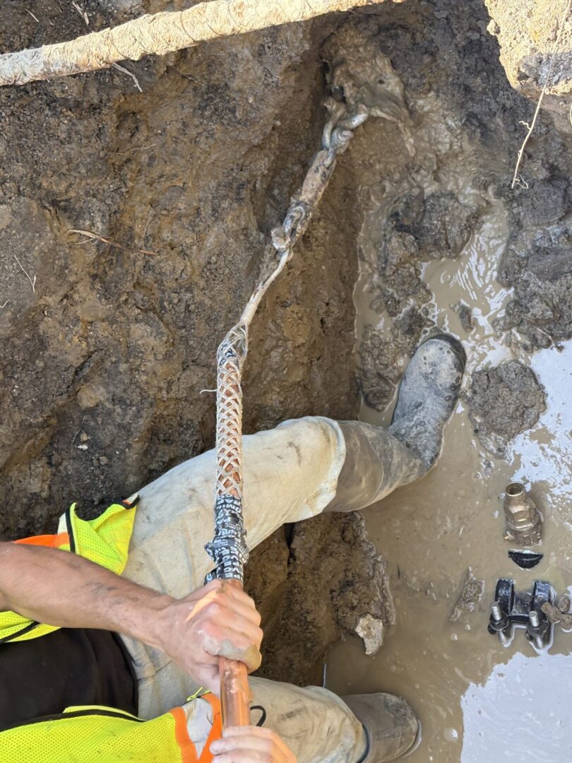 Person holding a knife with a handle wrapped in tape near a stone wall.