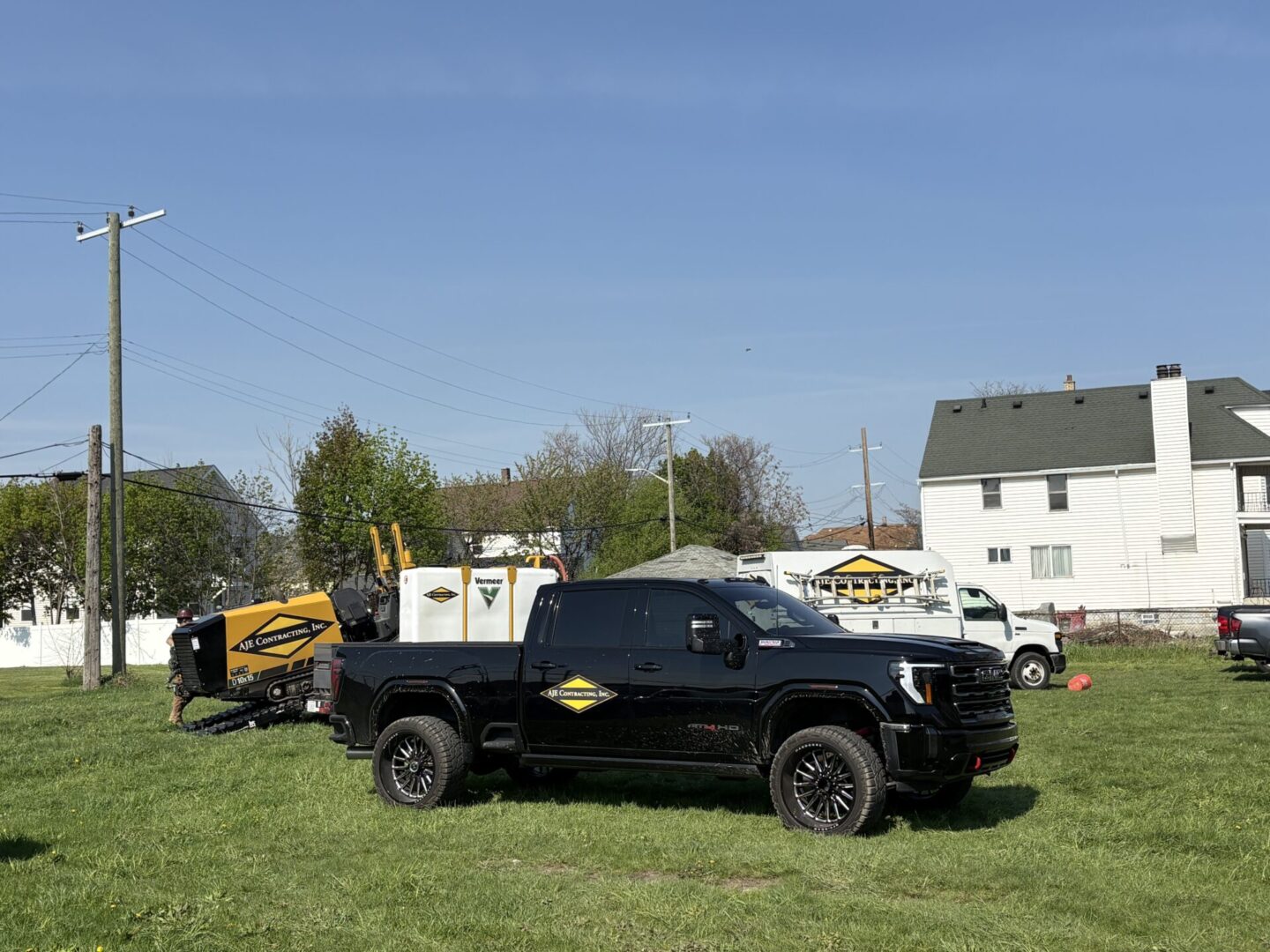 Black armored vehicle parked on grass near a yellow school bus and houses.