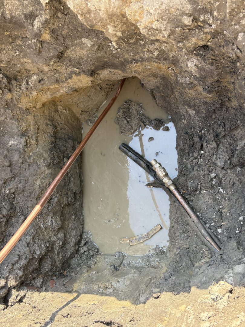 Concrete poured around metal rods in a ground hole.