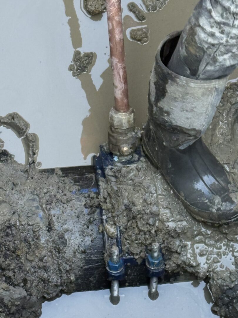 A plumbing setup with pipes and a boot in a messy, concrete-like environment.