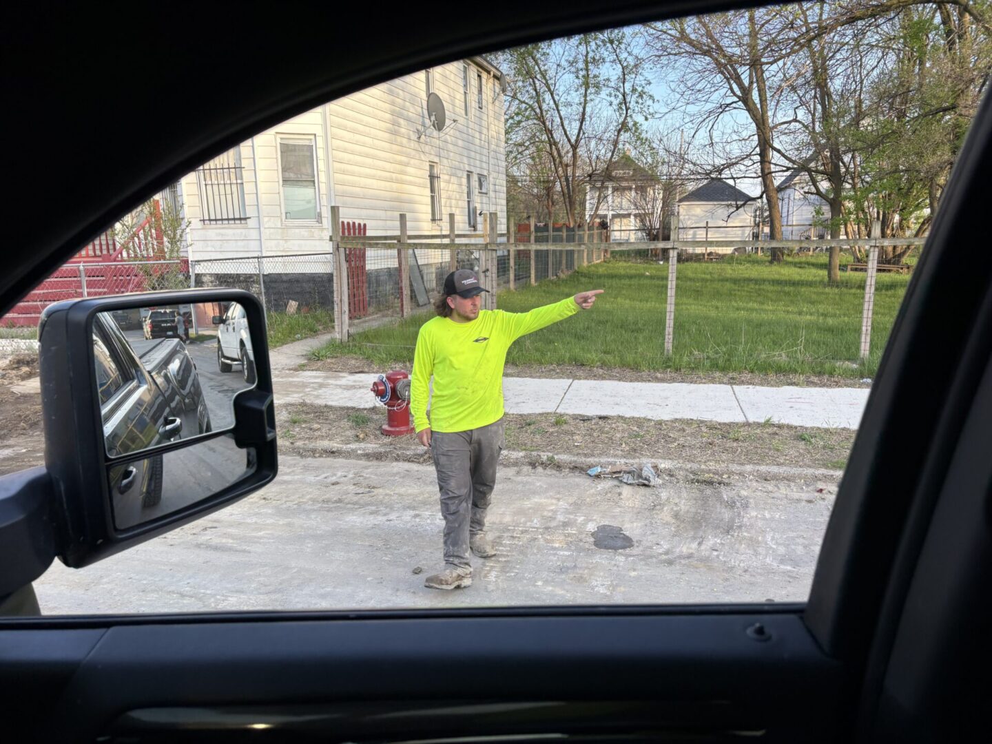 Person in a bright yellow jacket walking on a gravel path near residential buildings.