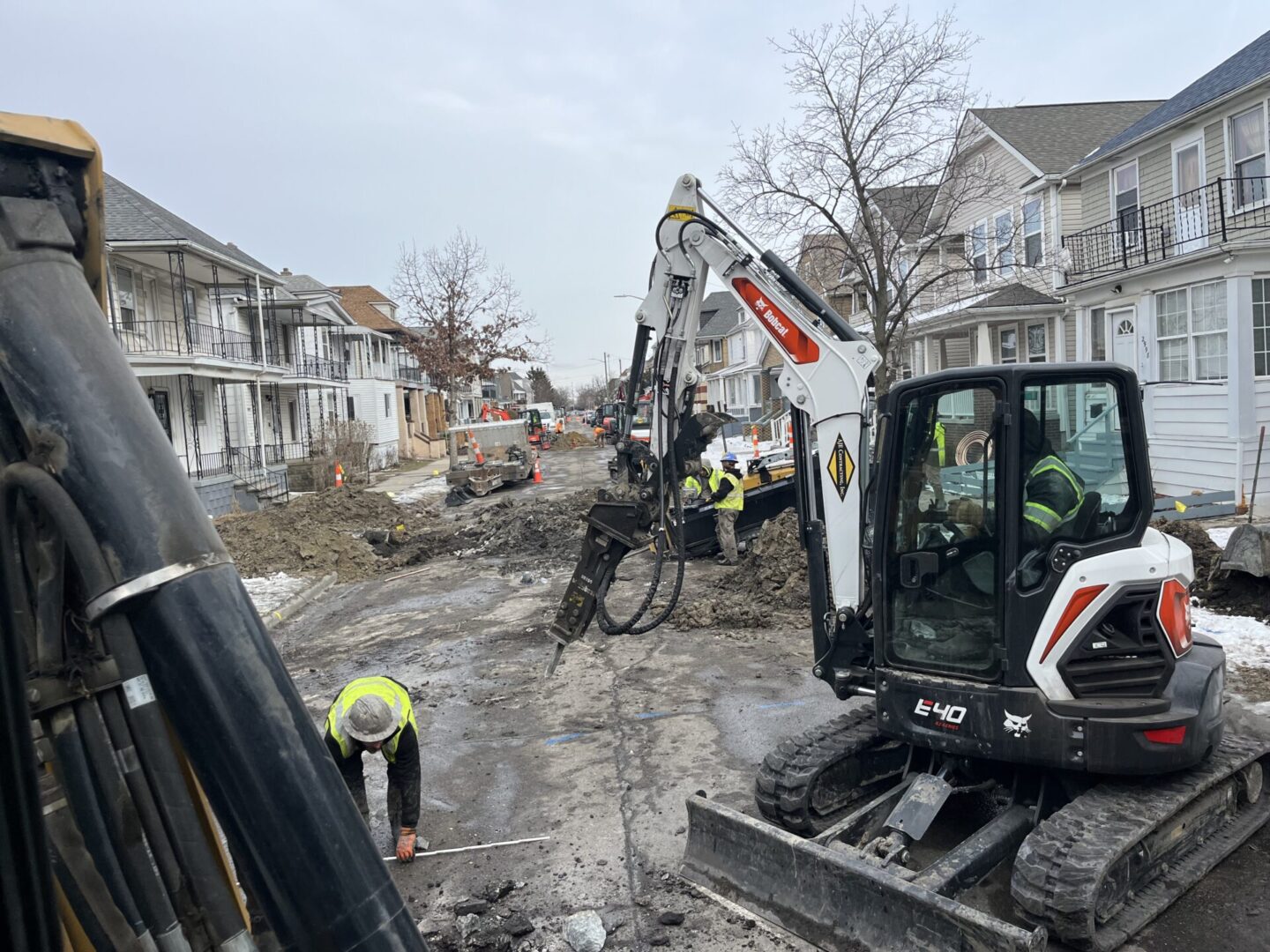 Workers using excavators to dig up a residential street for repairs.