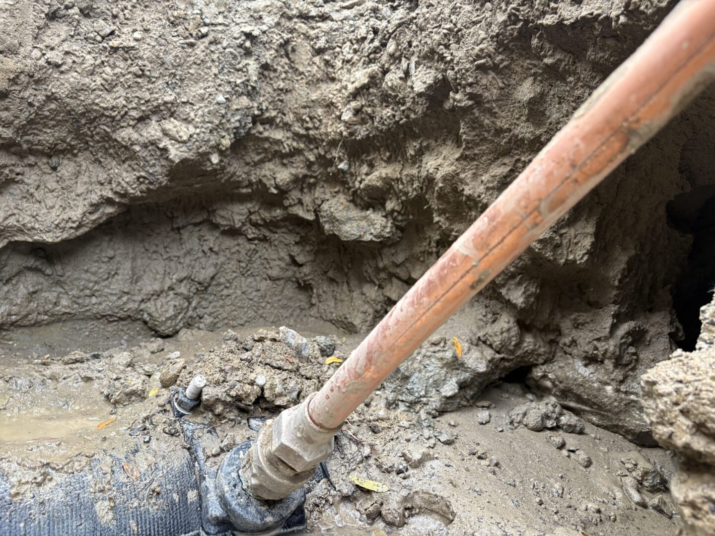 Close-up of a shovel digging into wet cement or mud.