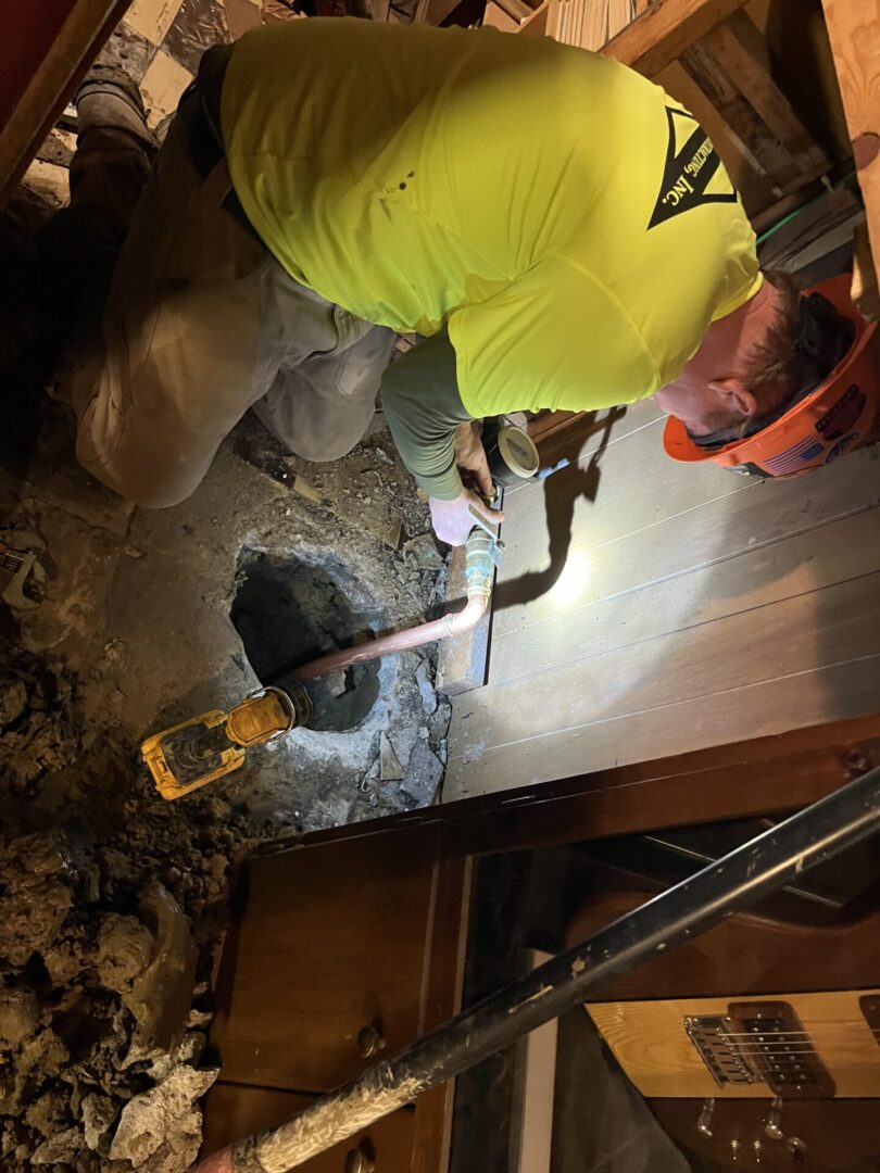 Worker uses jackhammer to break concrete floor inside building.