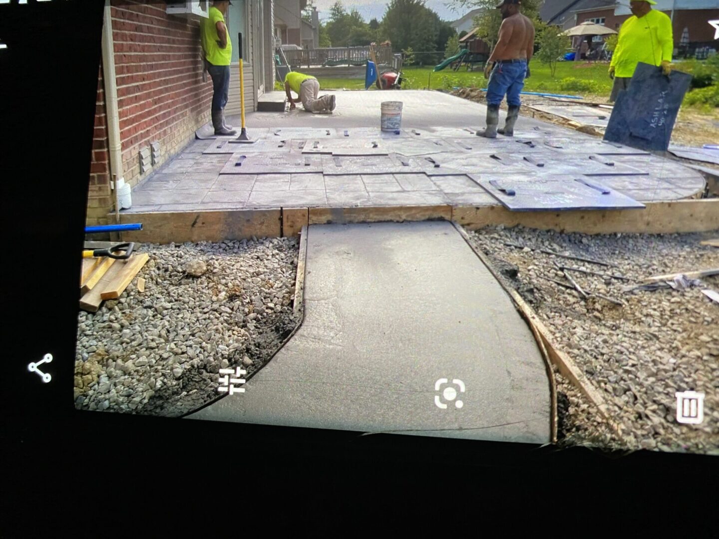 Freshly poured concrete pathway under construction with workers in the background.