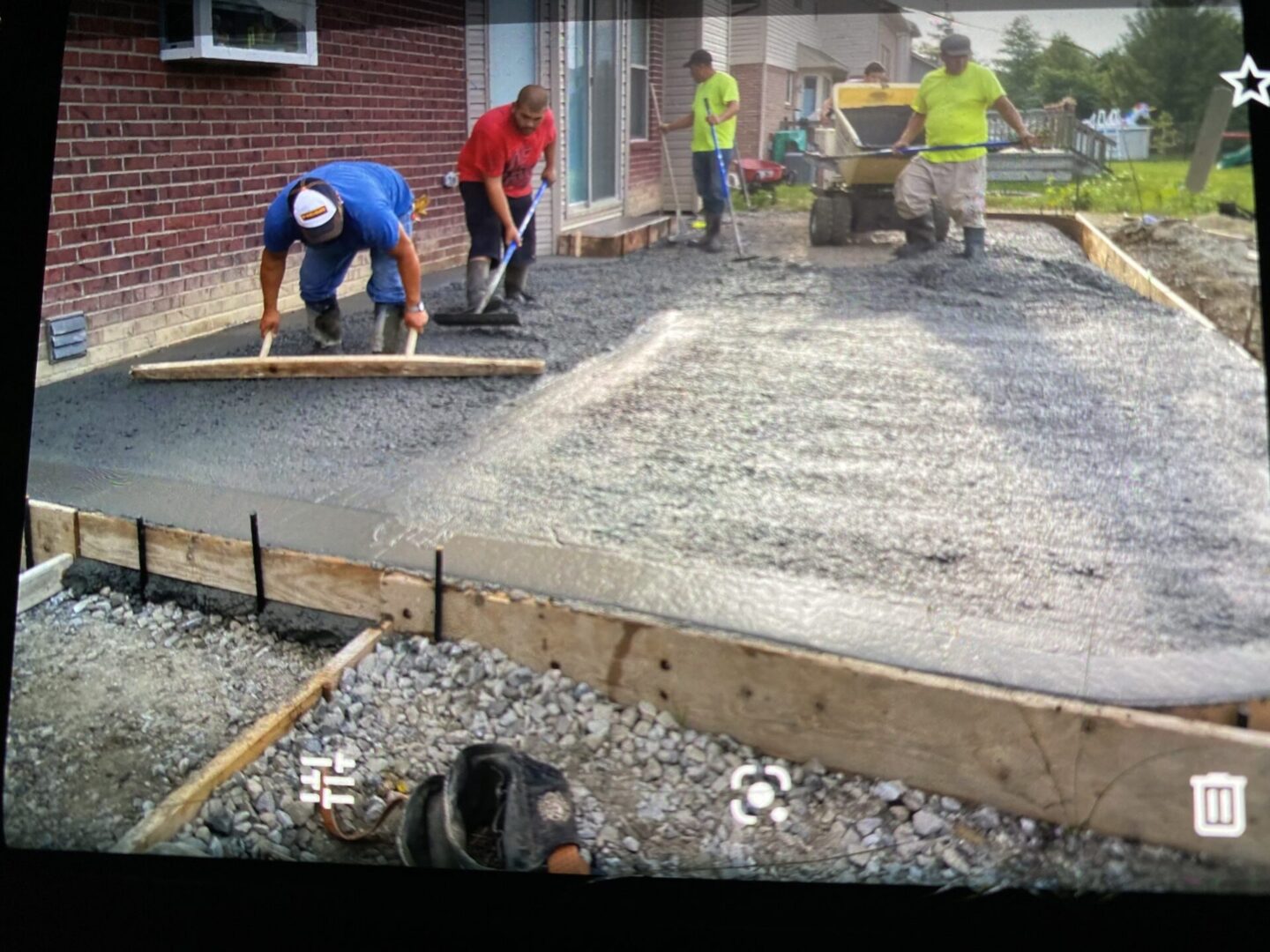Workers leveling wet concrete for a driveway.