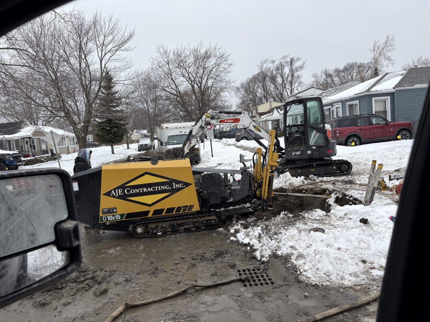 Construction equipment digging in snowy neighborhood street