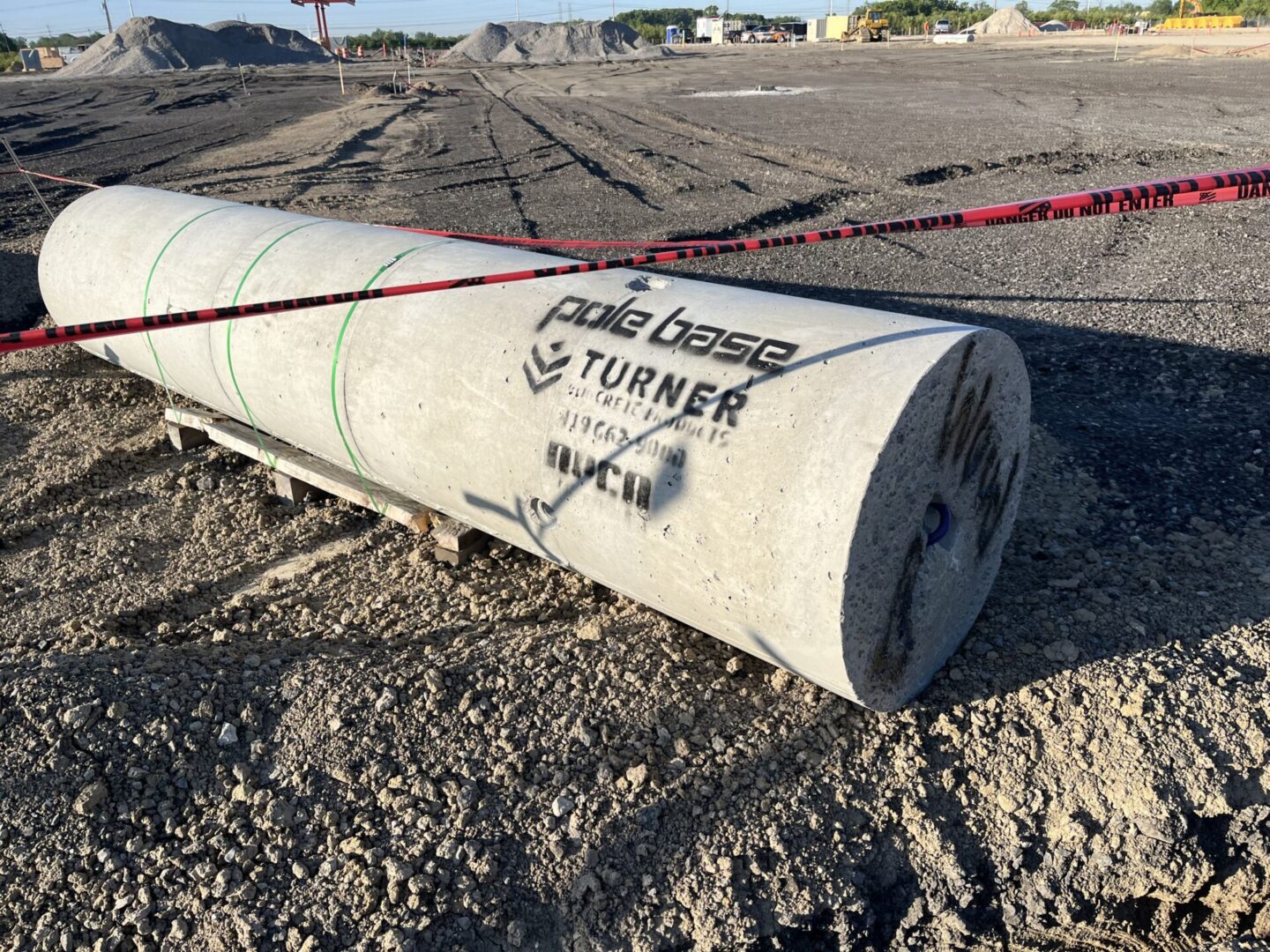 Concrete pole labeled for turning, lying on gravel.