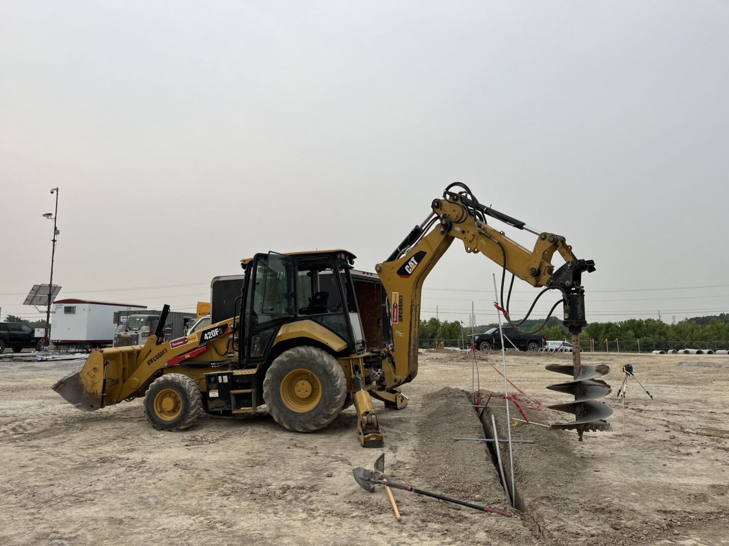 Construction machinery with an auger attachment on a foggy day.