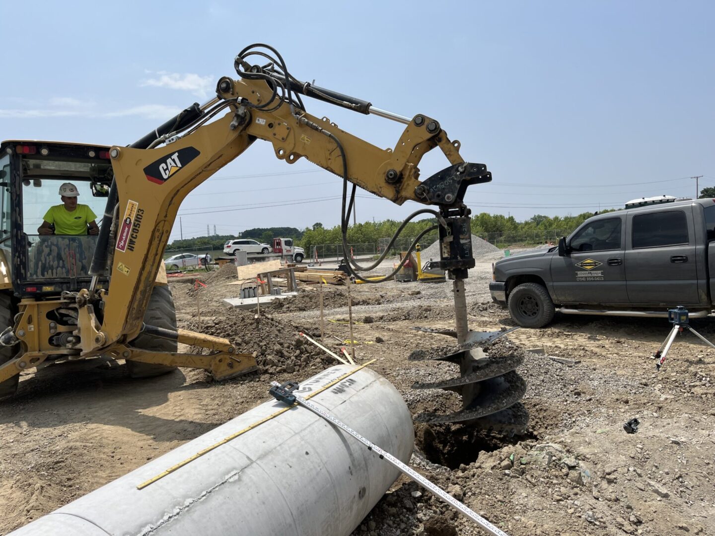 Construction site with excavator drilling into concrete.