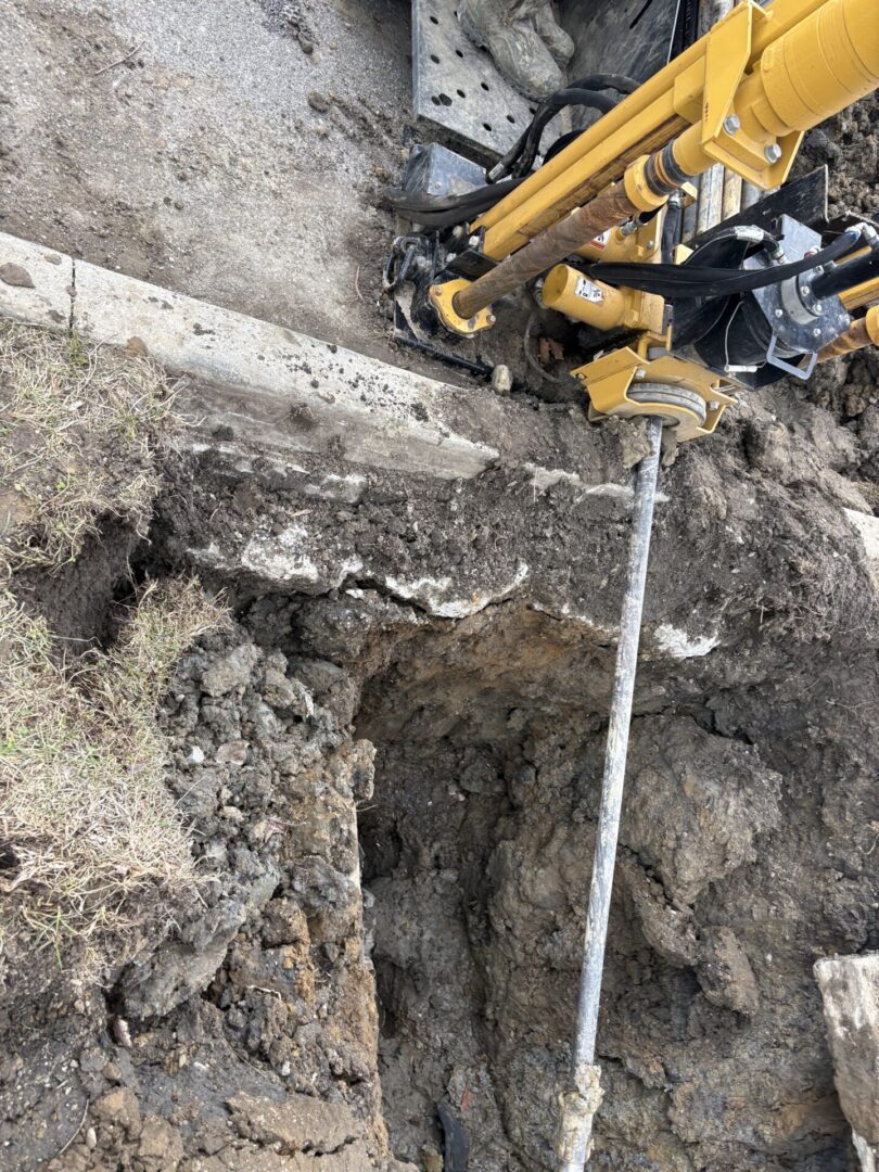 Yellow drilling rig and rod in trench