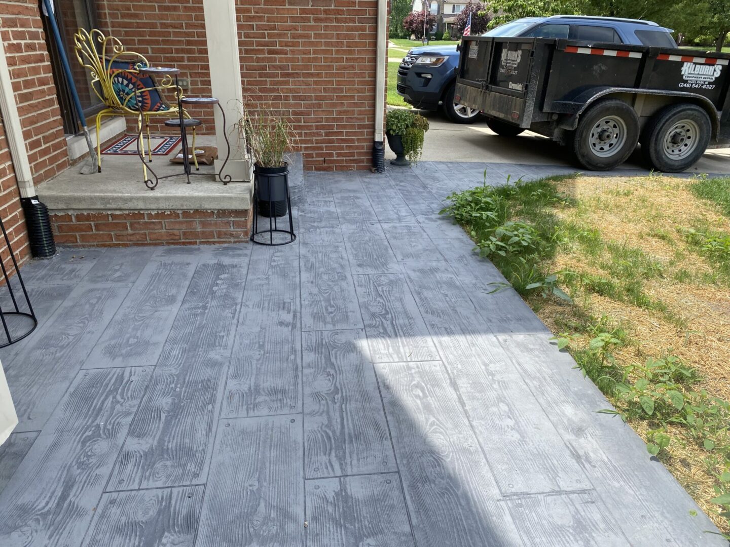 Newly paved patio area with stamped concrete and a black lantern.