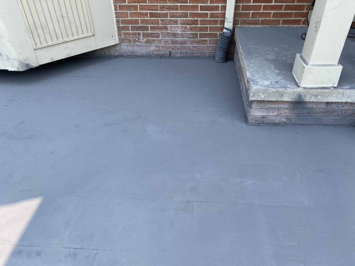 A freshly painted gray concrete floor near a brick wall and a small step.