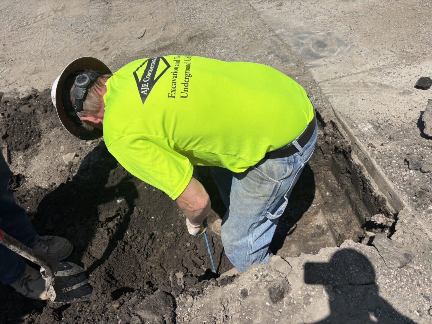 Worker in neon shirt digging roadside trench