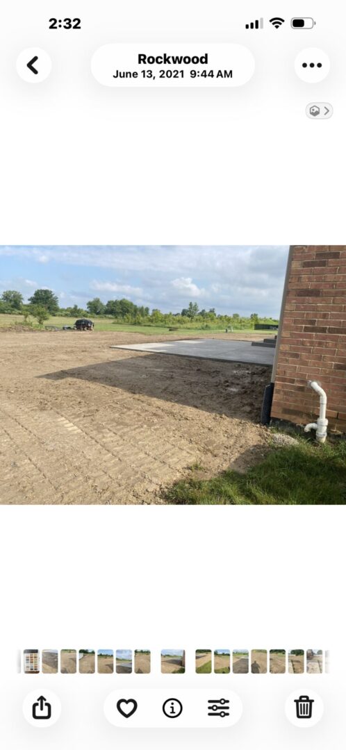 Cleared yard area beside a brick house with soil prepared for landscaping.