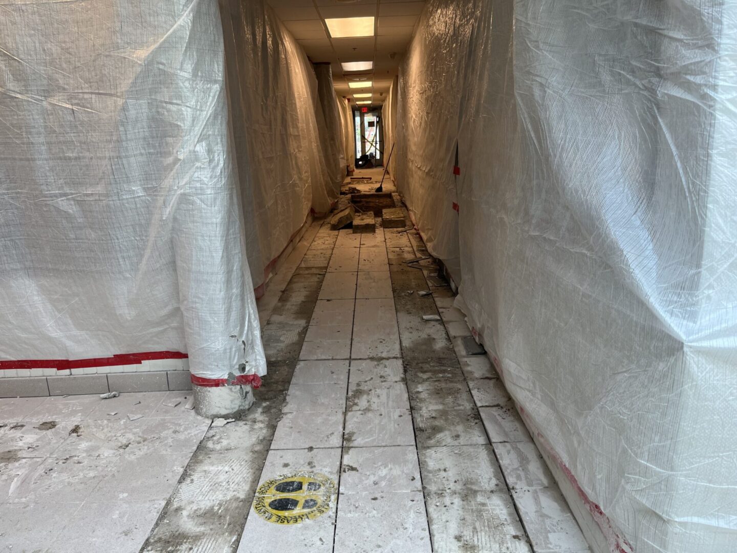 Construction corridor covered with plastic sheets and tiled floor.