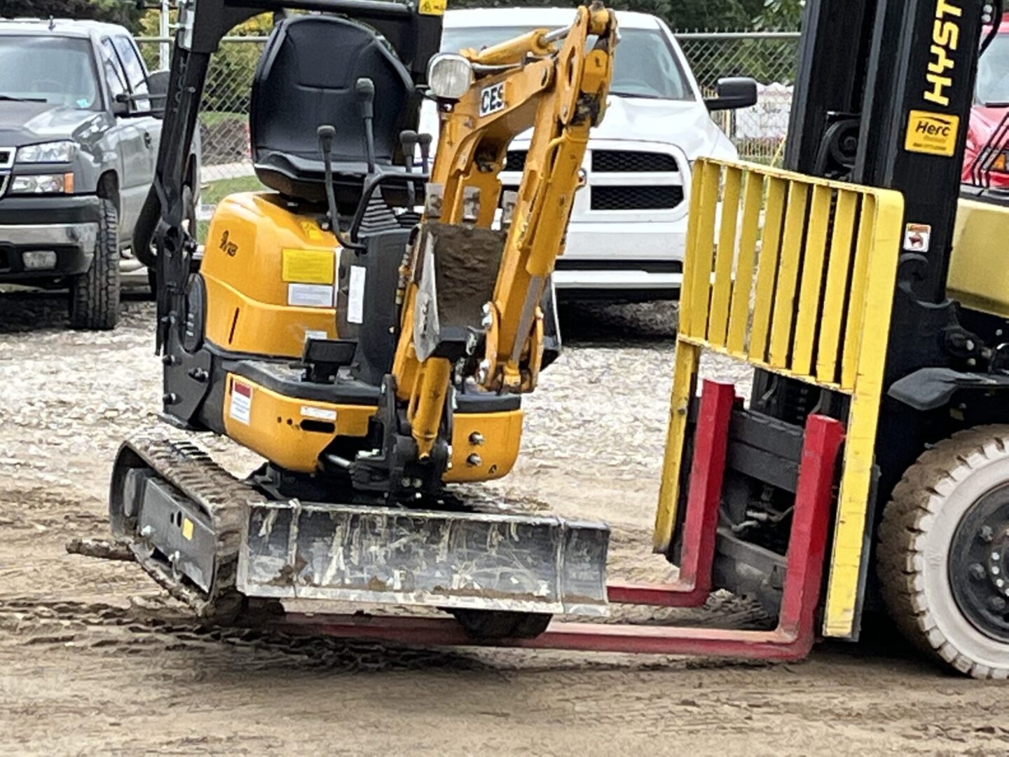 A small yellow excavator with a forklift attachment.