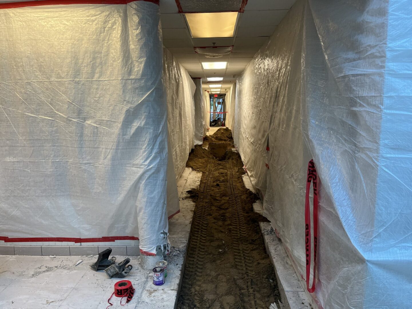 Long narrow hallway under renovation covered in plastic sheeting.
