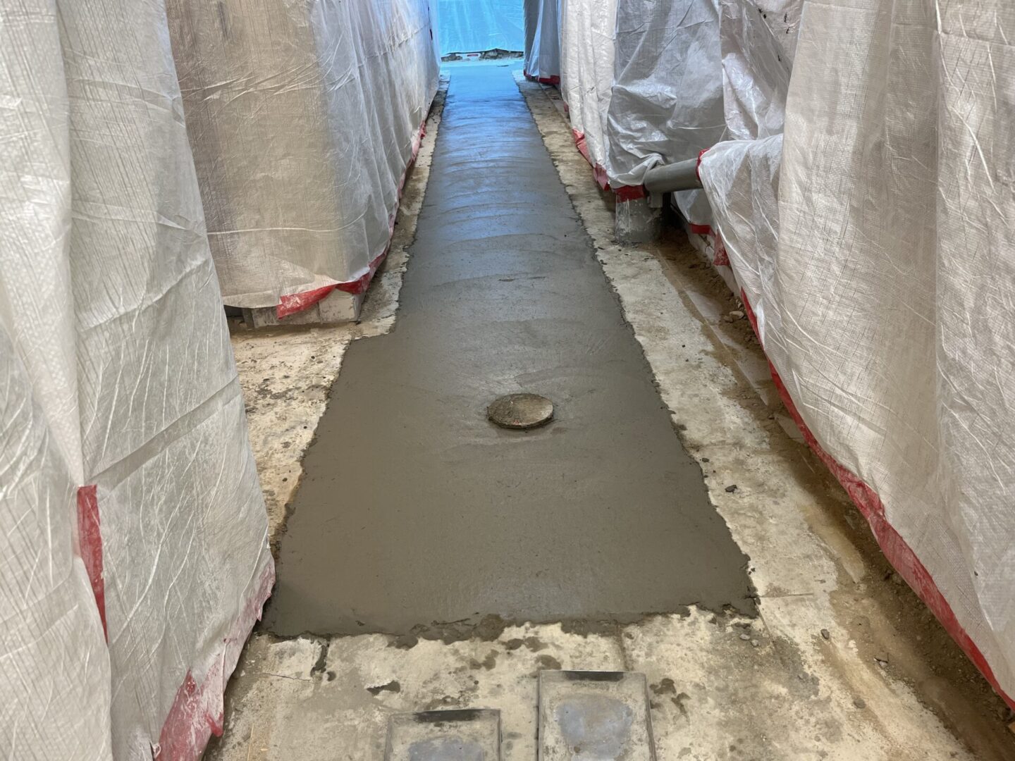 Freshly poured concrete pathway between covered structures.