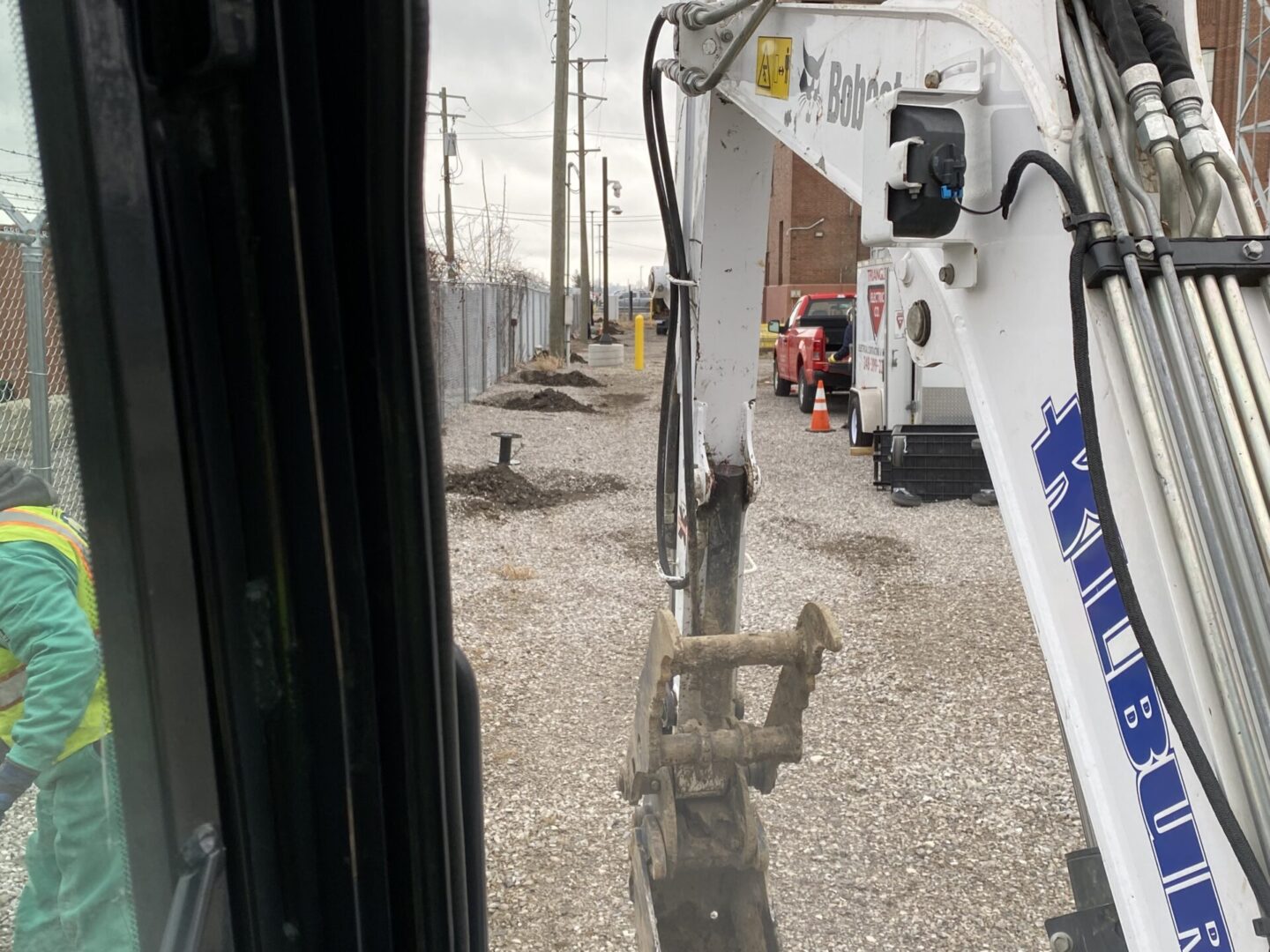 View from excavator cabin showing digging arm at construction site.