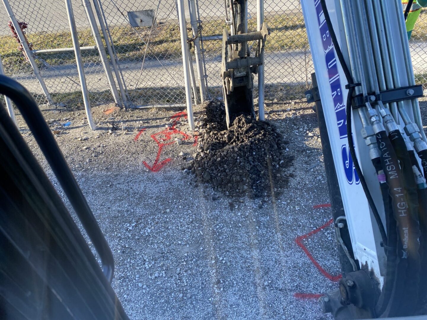 A pile of animal droppings near a fence and machinery.
