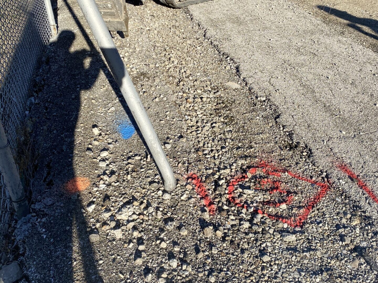 Concrete pavement with a metal pipe and red spray paint markings.