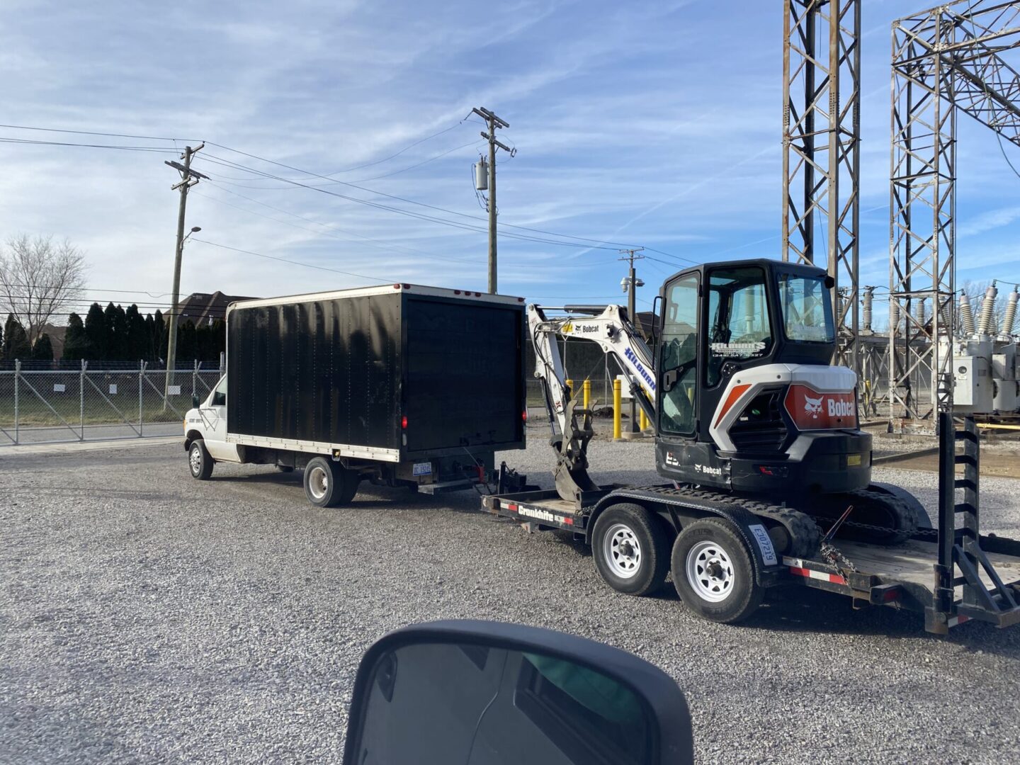 Compact excavator loaded on trailer attached to a truck.